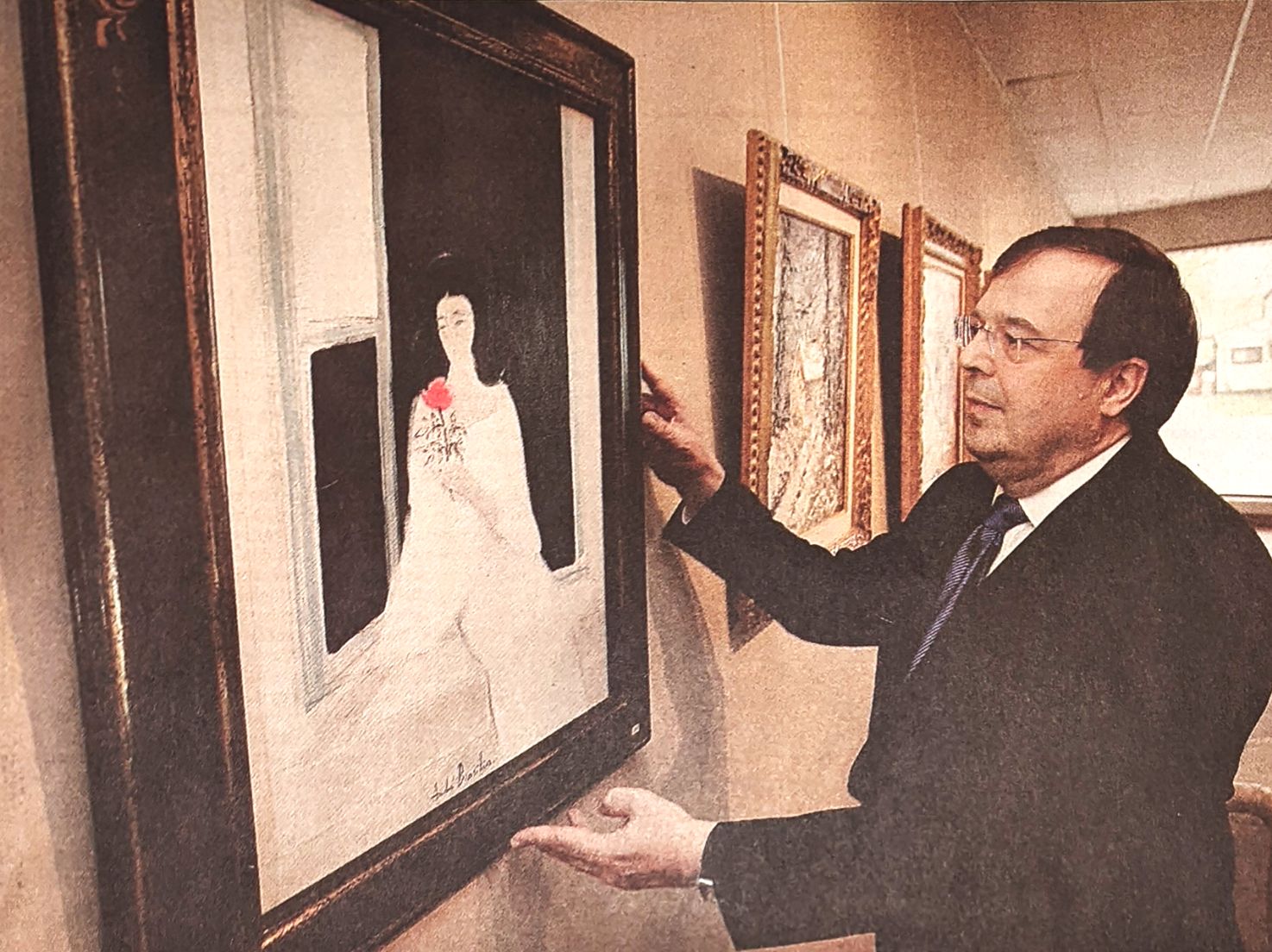 Dr. Allen Wahby showing a work on the wall at his gallery. 